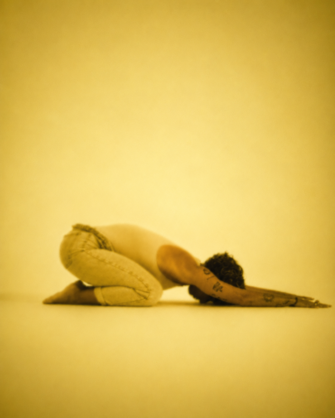 A figure resting in child's pose, bathed in golden light.